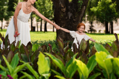 cropped shot of happy mother and daughter holding hands while walking in park